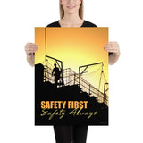 A workplace safety poster showing a construction site and construction workers being silhouetted by a bright and beautiful sunset of different shades of orange with the slogan safety first, safety always.