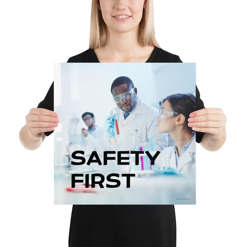 A safety poster showing two lab workers collaborating on a project in a lab while wearing full PPE with the slogan safety first.