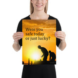 A workplace safety poster showing workers on a construction site being silhouetted in black with a sunset of orange hues in the background with the slogan were you safe today, or just lucky?