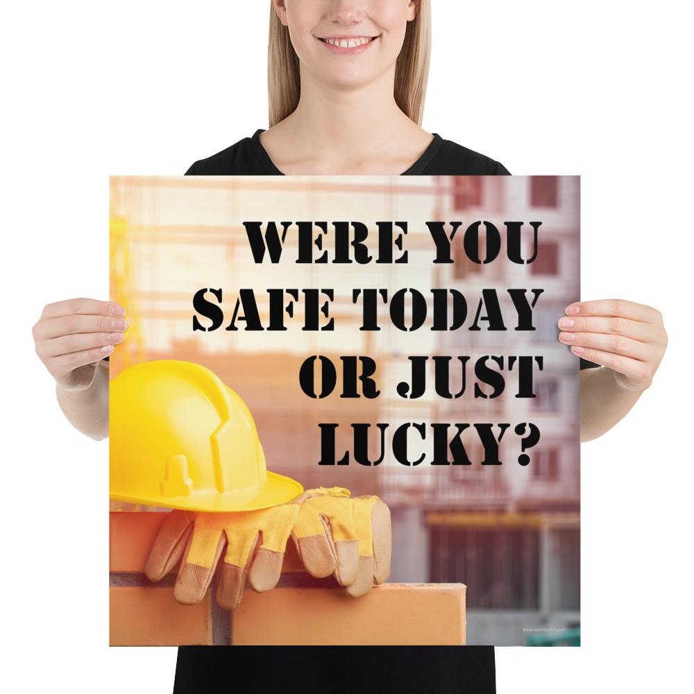 A workplace safety poster showing a yellow hard hat and some gloves sitting on a brick wall on a construction site with the slogan were you safe today, or just lucky written in black stencil font.
