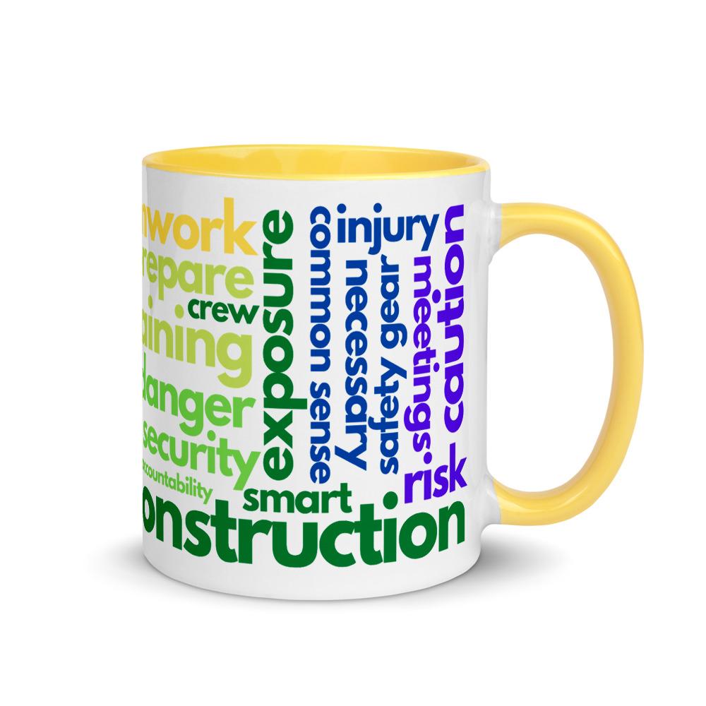 White ceramic mug with safety terms like hard hats, protection, and encourage, in a rainbow pattern across the mug with a yellow rim, inside, and handle.