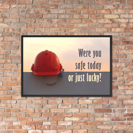 A workplace safety poster showing a red hard hat sitting on a grey wall with a dreamy sunset background and the slogan were you safe today, or just lucky?