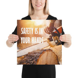 A safety poster showing a close-up of a man's hands holding a chainsaw sawing through a log with sawdust flying everywhere with the text safety is in your hands to the left.