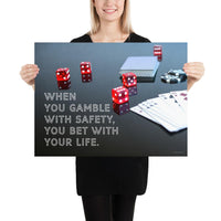 A workplace safety poster of a glossy black table with red dice, playing cards, and poker chips strewn everywhere with a safety slogan in the bottom left corner.