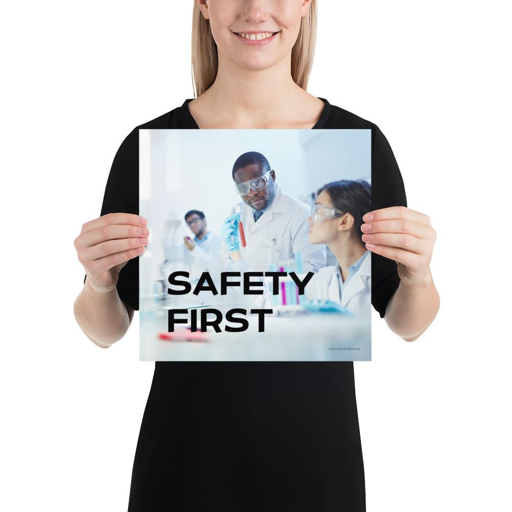 A safety poster showing two lab workers collaborating on a project in a lab while wearing full PPE with the slogan safety first.