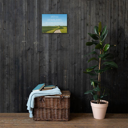 A workplace safety poster depicting a beautiful sunny day with a bright blue sky and a lush green field being cut down the middle by a dirt road leading off into the countryside with the text safety is a continuing journey, not a final destination.