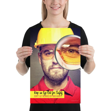 A workplace safety poster showing a portrait of a man wearing a hardhat and safety glasses with a magnifying glass magnifying one eye with the slogan, keep an eye out for safety, don't get blinded by bad habits.