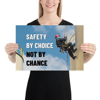 A fully harnessed man wearing a hard hat scaling the side of a building with a bright blue sky and clouds in the background with the text safety by choice, not by chance in bold text to his left.