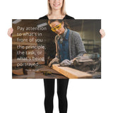 Workplace safety poster of a young female woodworker wearing safety glasses and gloves and sanding a two by four in her shop with a safety quote to the left.