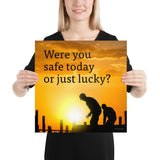 A workplace safety poster showing workers on a construction site being silhouetted in black with a sunset of orange hues in the background with the slogan were you safe today, or just lucky?