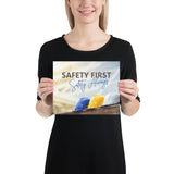 A workplace safety poster showing a white, a yellow, and a blue hardhat sitting on a wall with the slogan safety first, safety always.