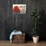 A workplace safety poster depicting a red hard hat sitting on a concrete wall with a dreamy pink sunset in the background with the text never give safety a day off to the right.