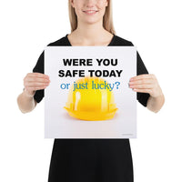 A workplace safety poster showing a yellow hard hat on a plain white background with the slogan were you safe today, or just lucky?