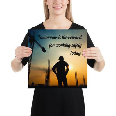 A safety poster showing a worker on a construction site being silhouetted by a sunset of orange and blue colors with the slogan tomorrow is the reward for working safely today.