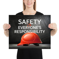 A workplace safety poster showing a red hard hat in front of a grey, industrial-looking background with the slogan safety is everyone's responsibility.