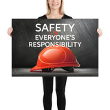 A workplace safety poster showing a red hard hat in front of a grey, industrial-looking background with the slogan safety is everyone's responsibility.