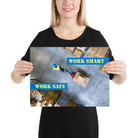 A safety poster showing a bird's-eye view of a worker in a warehouse pulling boxes on a pallet jack with the slogan work smart, work safe.