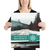 A safety poster showing a picture taken from the dashboard of a car showing an iced over road in the mountains with the slogan don't get caught in the cold, buckle up and stay safe.