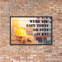A workplace safety poster showing a yellow hard hat and some gloves sitting on a brick wall on a construction site with the slogan were you safe today, or just lucky written in black stencil font.