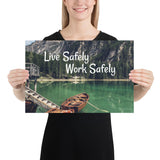 A workplace safety poster depicting a beautiful landscape of mountains in the background of a lake with a little wooden boat in the lake with text saying live safely work safely.