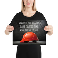 A workplace safety poster showing a bright red hard hat with an ominous black background with the slogan living with your mistakes is harder than you think, wear your safety gear.