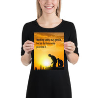 A workplace safety poster showing a construction site and construction workers being silhouetted by a bright and beautiful sunset of different shades of orange with the slogan working safely may get old, but so do those who practice it.