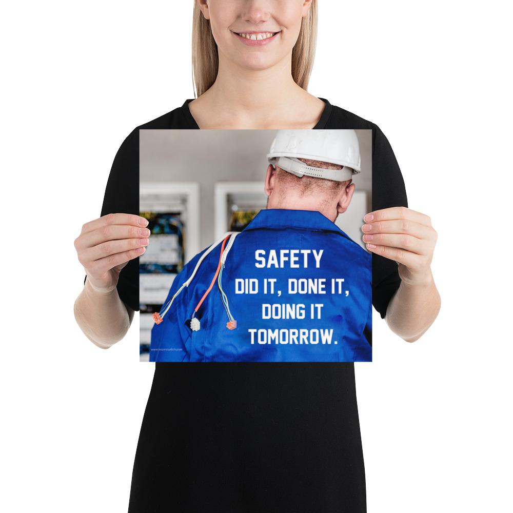 Safety poster showing an electrician wearing a hard hat and holding cables working on an electrical panel with text on the back of his bright blue shirt.
