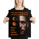 An eye safety poster of a close up of a mans face with his eyes wide open with text and PPE infographics covering his left eye.