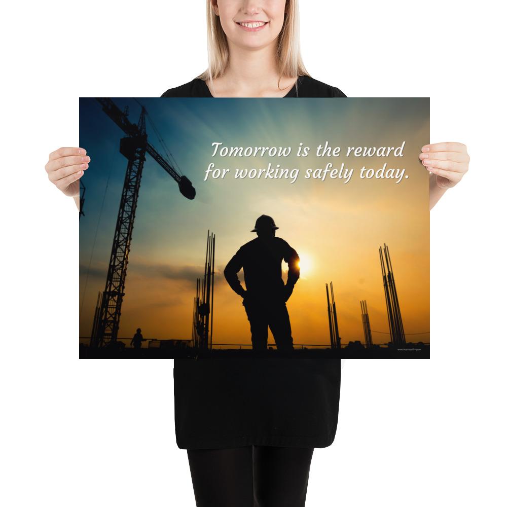 A safety poster showing a worker on a construction site being silhouetted by a sunset of orange and blue colors with the slogan tomorrow is the reward for working safely today.