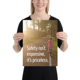 A safety poster showing a little girl riding her bike down a road on a sunny day with the slogan safety isn't expensive, it's priceless.