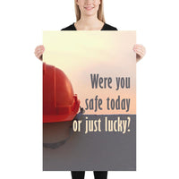 A workplace safety poster showing a red hard hat sitting on a grey wall with a dreamy sunset background and the slogan were you safe today, or just lucky?