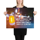 A workplace safety poster depicting a bright orange construction traffic light in the foreground of a blurry nighttime cityscape with a safety quote by William Blake.