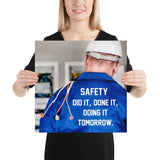 Safety poster showing an electrician wearing a hard hat and holding cables working on an electrical panel with text on the back of his bright blue shirt.
