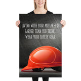 A workplace safety poster showing a bright red hard hat with an ominous black background with the slogan living with your mistakes is harder than you think, wear your safety gear.