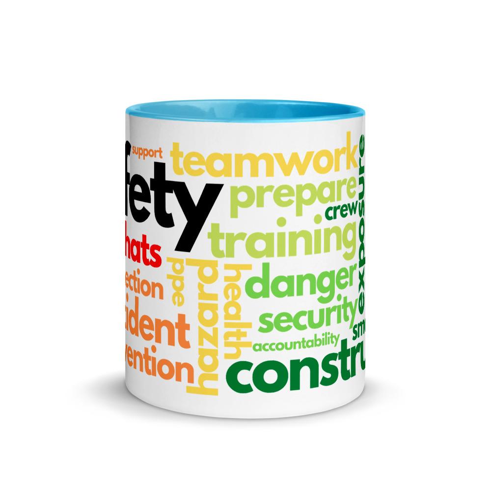 White ceramic mug with safety terms like hard hats, protection, and encourage, in a rainbow pattern across the mug with a blue rim, inside, and handle.
