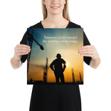 A safety poster showing a worker on a construction site being silhouetted by a sunset of orange and blue colors with the slogan tomorrow is the reward for working safely today.