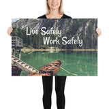 A workplace safety poster depicting a beautiful landscape of mountains in the background of a lake with a little wooden boat in the lake with text saying live safely work safely.