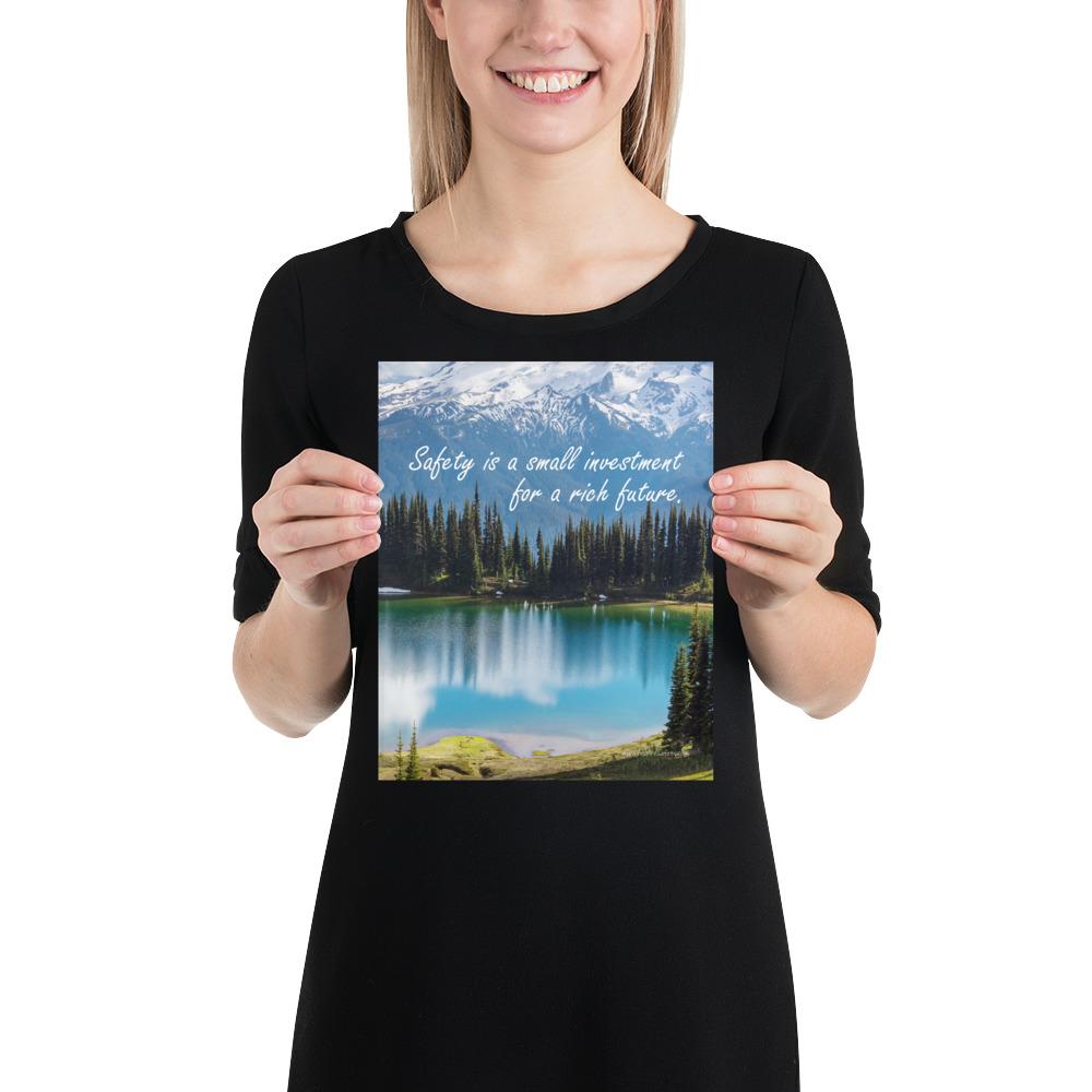 A workplace safety poster depicting a beautiful pond in the foreground, lush evergreens in the middle ground and snow-capped mountains in the background with text saying safety is a small investment for a rich future.