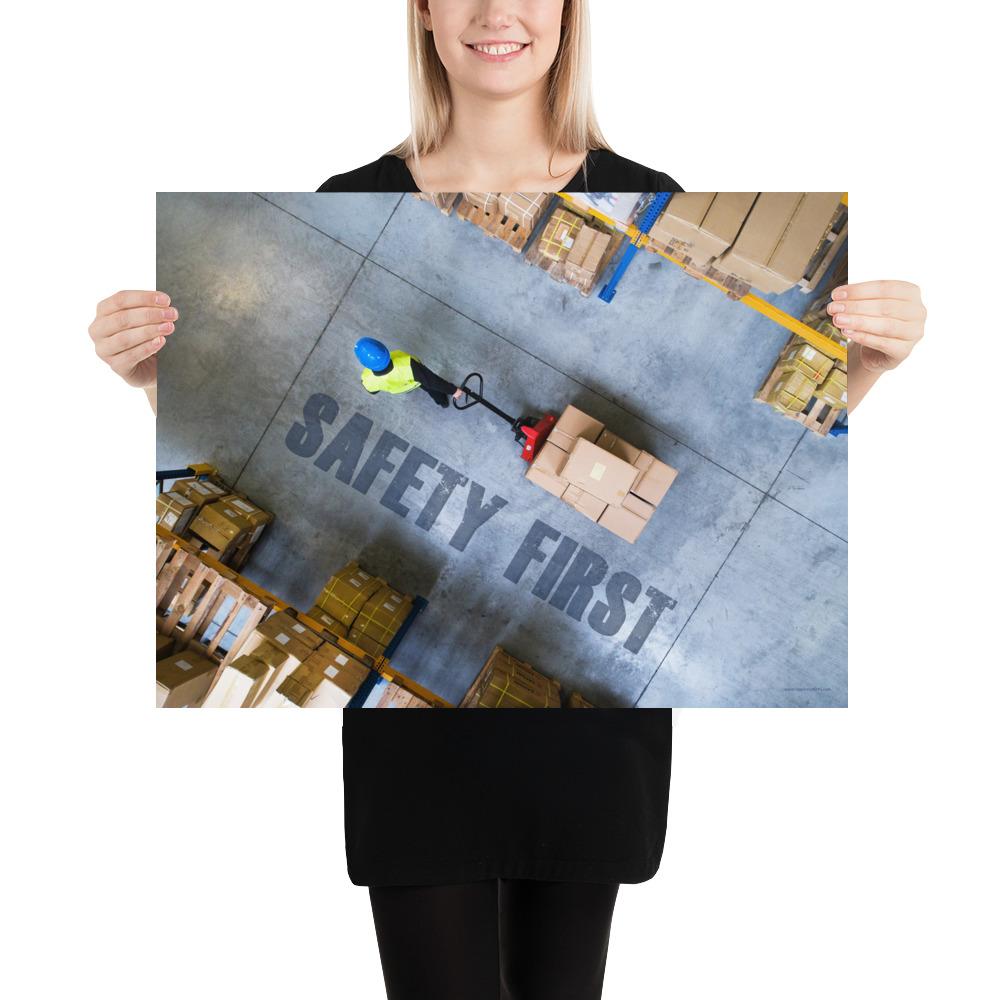 A safety poster showing a bird's-eye view of a worker in a warehouse pulling boxes on a pallet jack with the slogan safety first in bold letters.