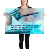 Workplace safety poster of a close up of a woman's eyes wearing safety glasses inspecting a sample on a microscope with safety quote written at the bottom.