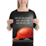 A workplace safety poster showing a bright red hard hat with an ominous black background with the slogan living with your mistakes is harder than you think, wear your safety gear.