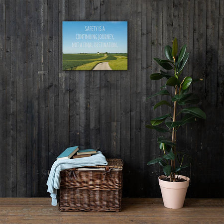 A workplace safety poster depicting a beautiful sunny day with a bright blue sky and a lush green field being cut down the middle by a dirt road leading off into the countryside with the text safety is a continuing journey, not a final destination.