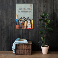 A workplace safety poster showing various tools such as a screwdriver, wrench, and pliers on a wooden table with the slogan don't be a fool use the proper tool.