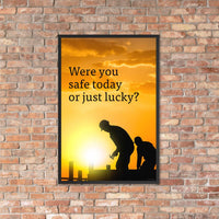 A workplace safety poster showing workers on a construction site being silhouetted in black with a sunset of orange hues in the background with the slogan were you safe today, or just lucky?