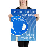 A hearing protection poster showing a bright blue construction sign with an illustration of a face wearing ear muffs with sound waves coming from the right and a safety slogan in the upper right and bottom right corners.