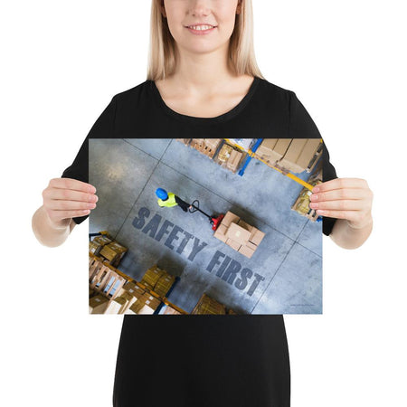 A safety poster showing a bird's-eye view of a worker in a warehouse pulling boxes on a pallet jack with the slogan safety first in bold letters.