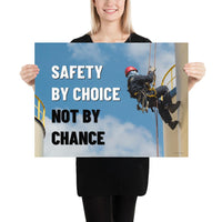 A fully harnessed man wearing a hard hat scaling the side of a building with a bright blue sky and clouds in the background with the text safety by choice, not by chance in bold text to his left.