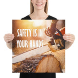 A safety poster showing a close-up of a man's hands holding a chainsaw sawing through a log with sawdust flying everywhere with the text safety is in your hands to the left.