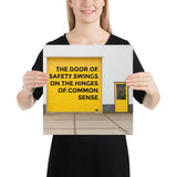 Workplace safety poster depicting a bright yellow garage door to a warehouse with a bold safety slogan on it with a smaller yellow door to the right.