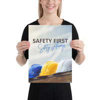 A workplace safety poster showing a white, a yellow, and a blue hardhat sitting on a wall with the slogan safety first, safety always.